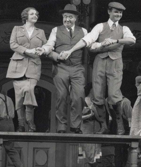 A production Photo from the musical Crazy For You; Stephen Temperley as Eugene Fodor, dancing on a table with Ronn Carrol and Amelia White
